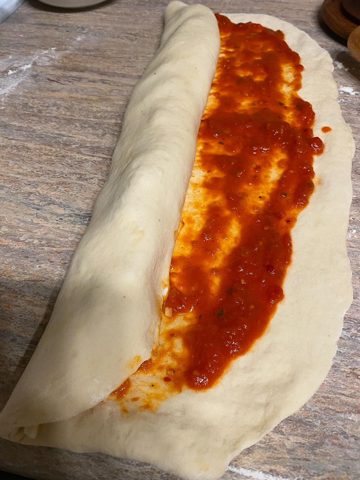 process of forming pizza roll against a light brown surface