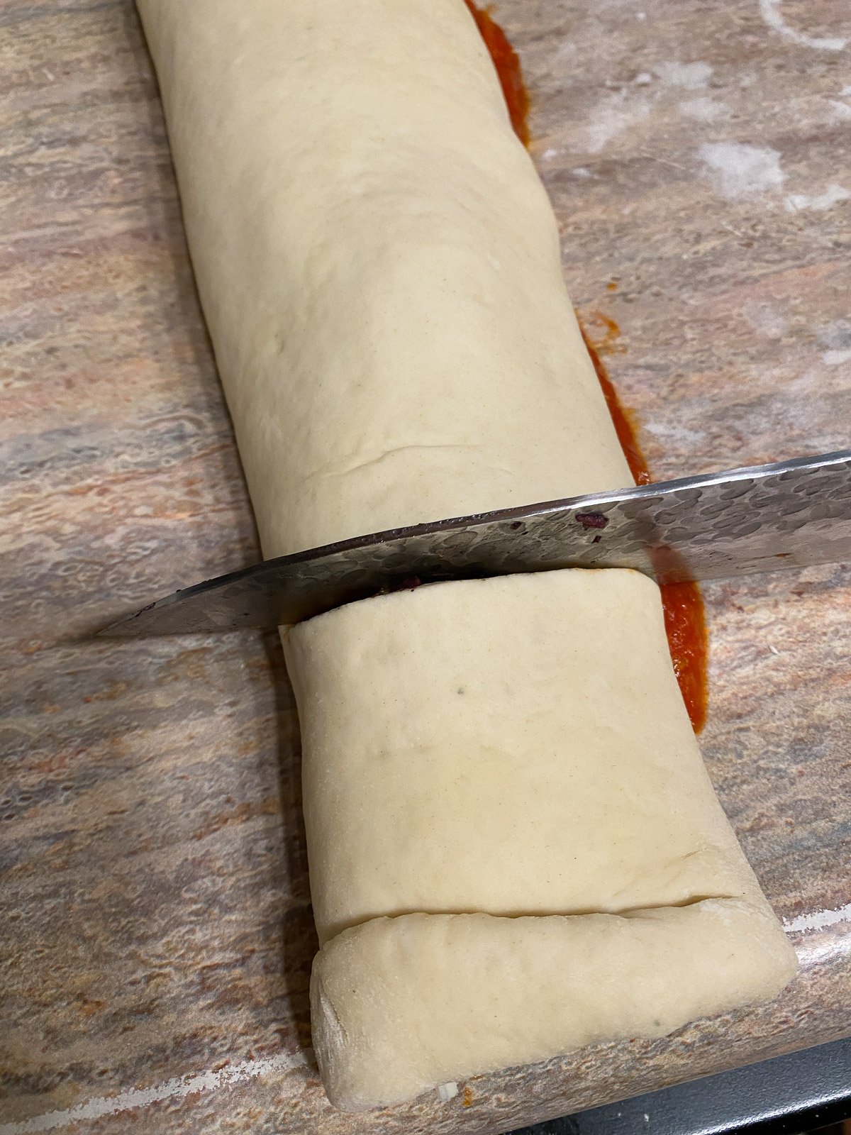 process of cutting pizza into rolls with a cutting knife