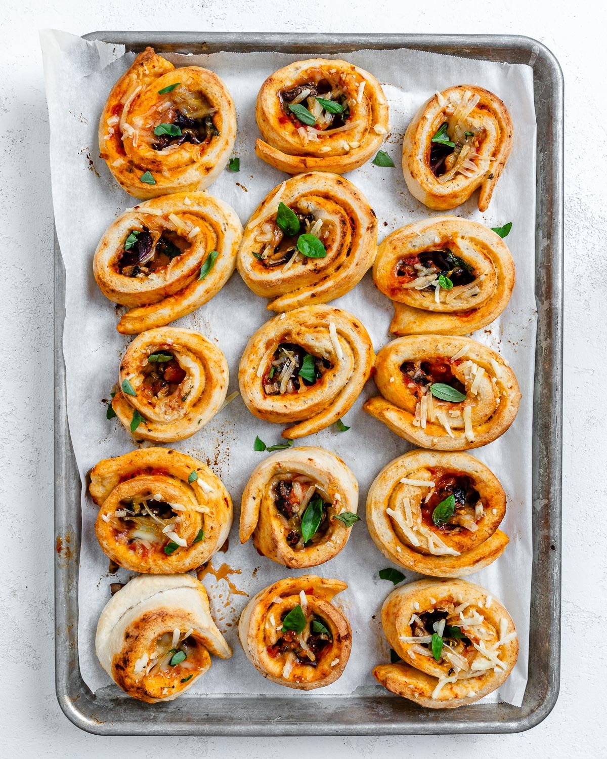 several completed vegan pizza rolls on a baking dish