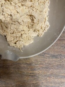 process of forming flour in a white bowl against a light brown surface