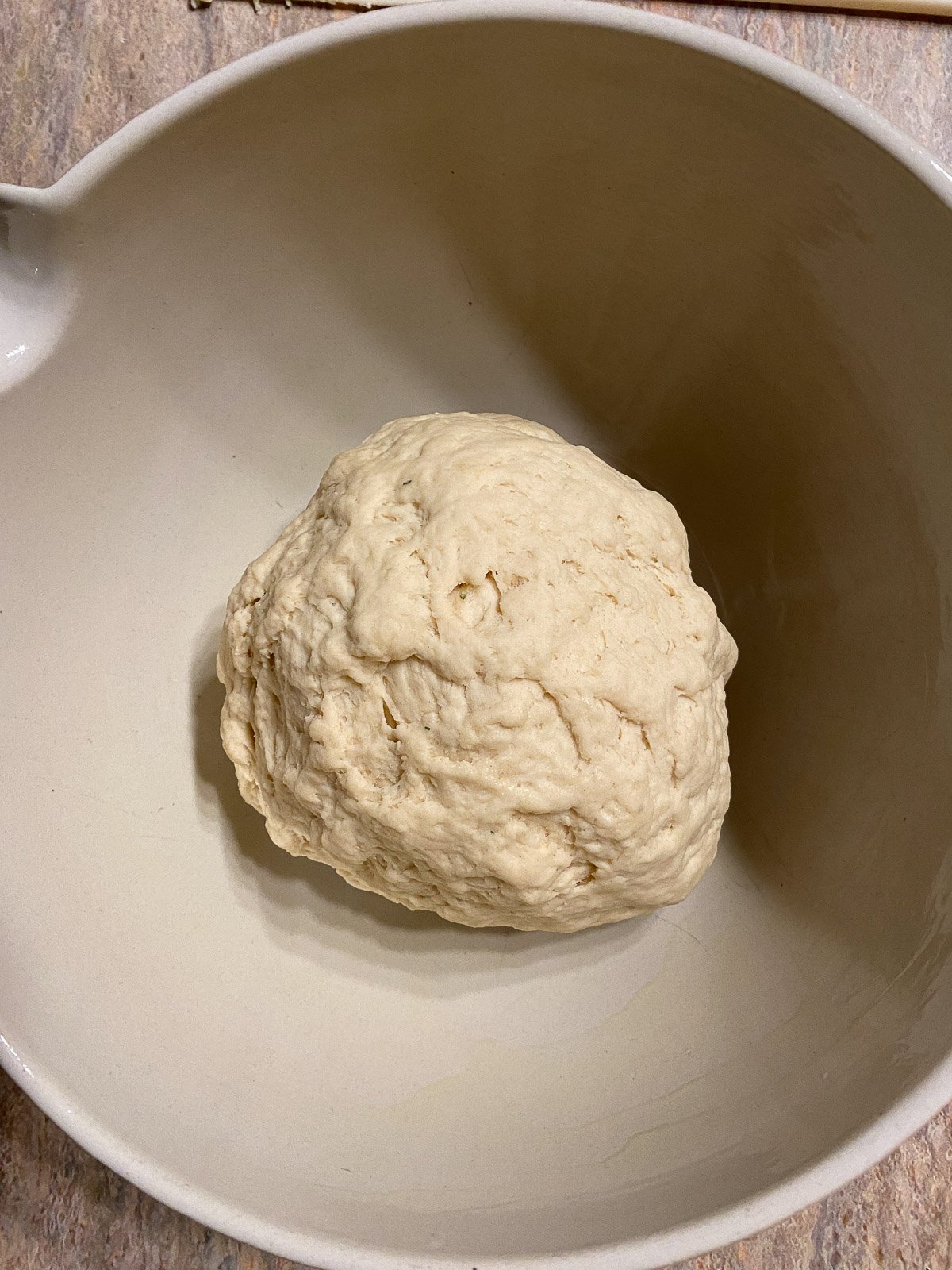 process of forming dough in a white bowl against a light brown surface
