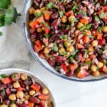 completed mixed bean salad in serving bowl and individual bowl against a white background
