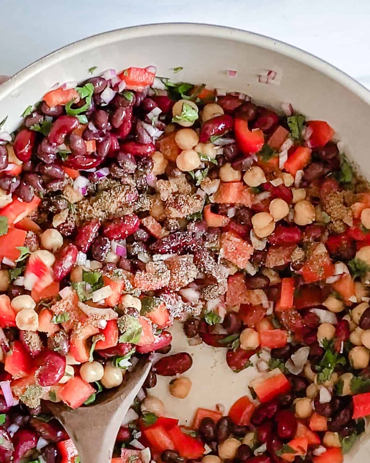 process of mixing ingredients of mixed bean salad in bowl