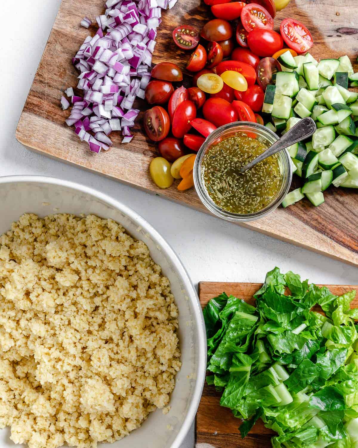chopped and cooked ingredients for Vegan Greek Millet Salad on a cutting board