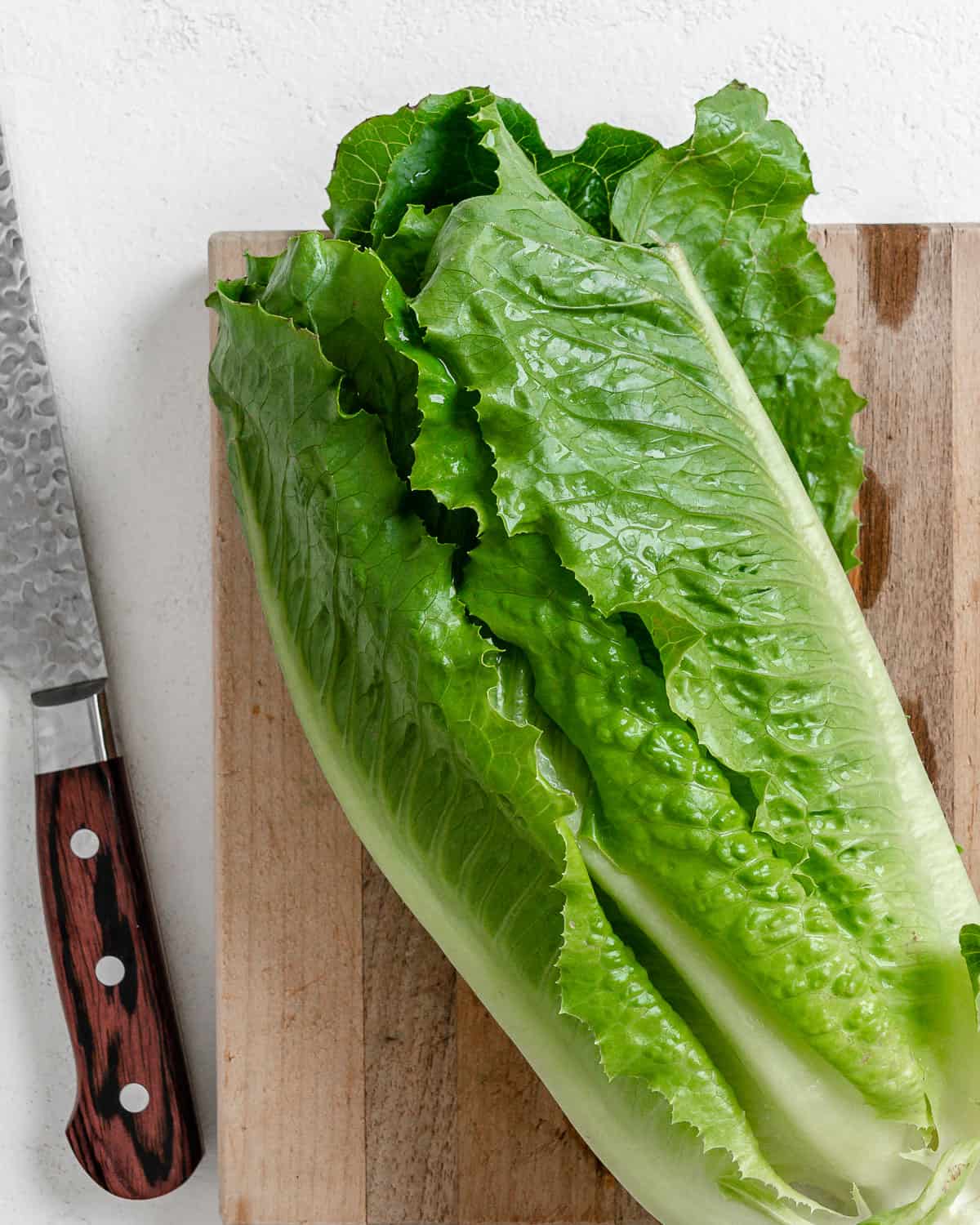 lettuce on a cutting board with a knife in the background