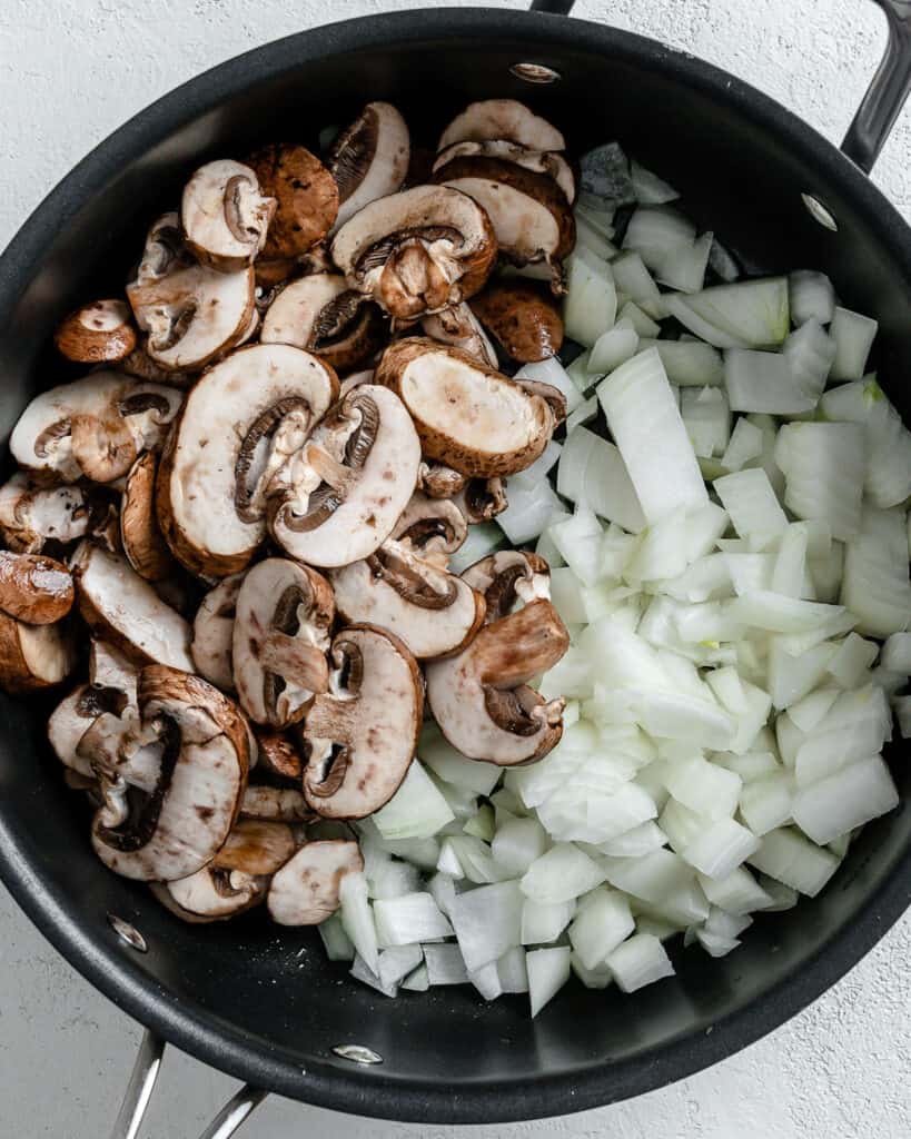 process shot of mushrooms and onions in a black pot
