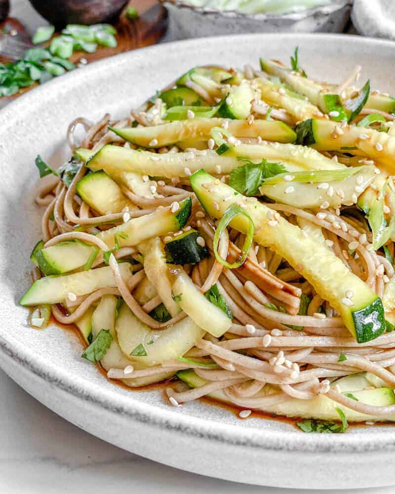 completed Vegan Warm Soba Salad with Cucumbers in white bowl against a white background