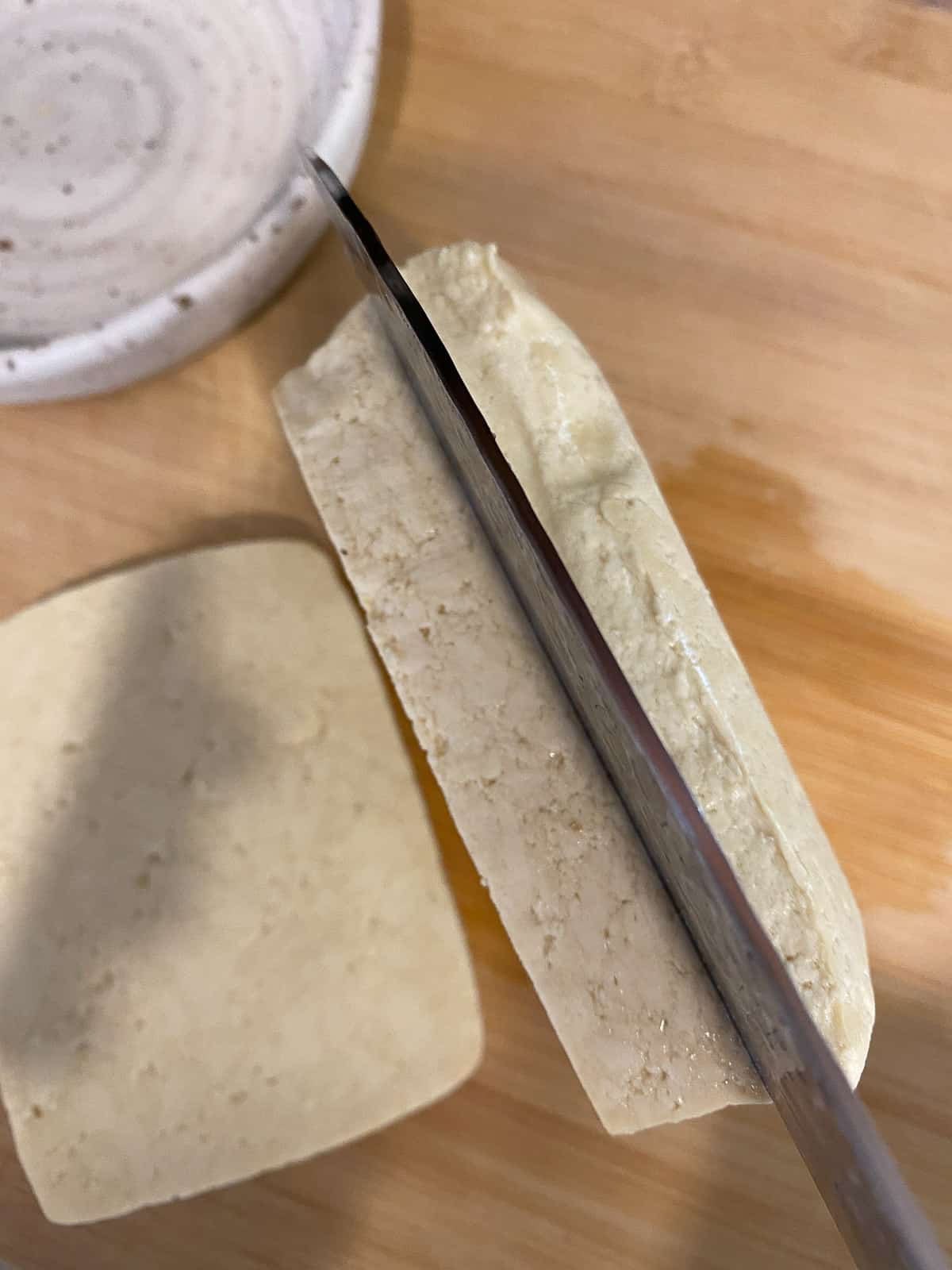 process shot of slicing tofu on a cutting board