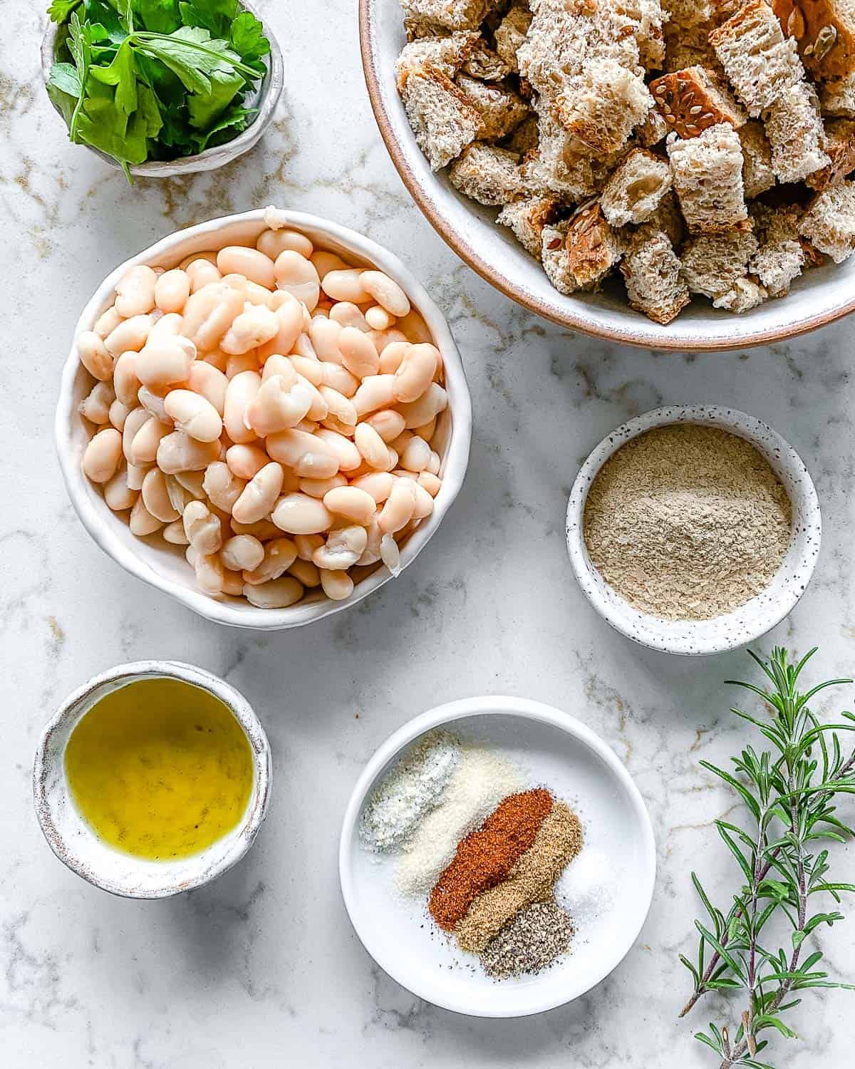 ingredients for white bean burgers measured out in white bowls against white surface