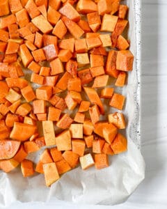 process showing roasted butternut squash being cut into cubes against a white background