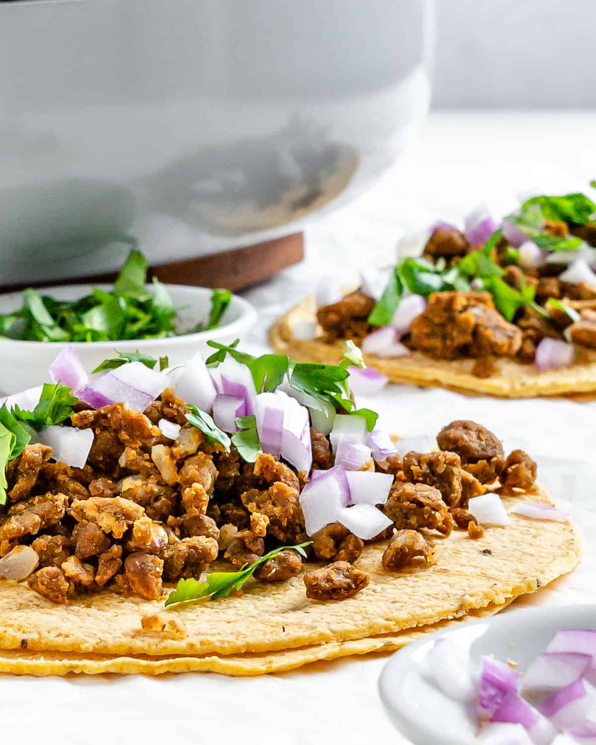 completed Plant Based Street Tacos with Lentils on a white surface with ingredients in the background