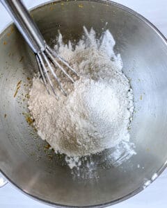 process of Orange Olive Oil Cake flour being mixed with wet ingredients in stainless steel bowl
