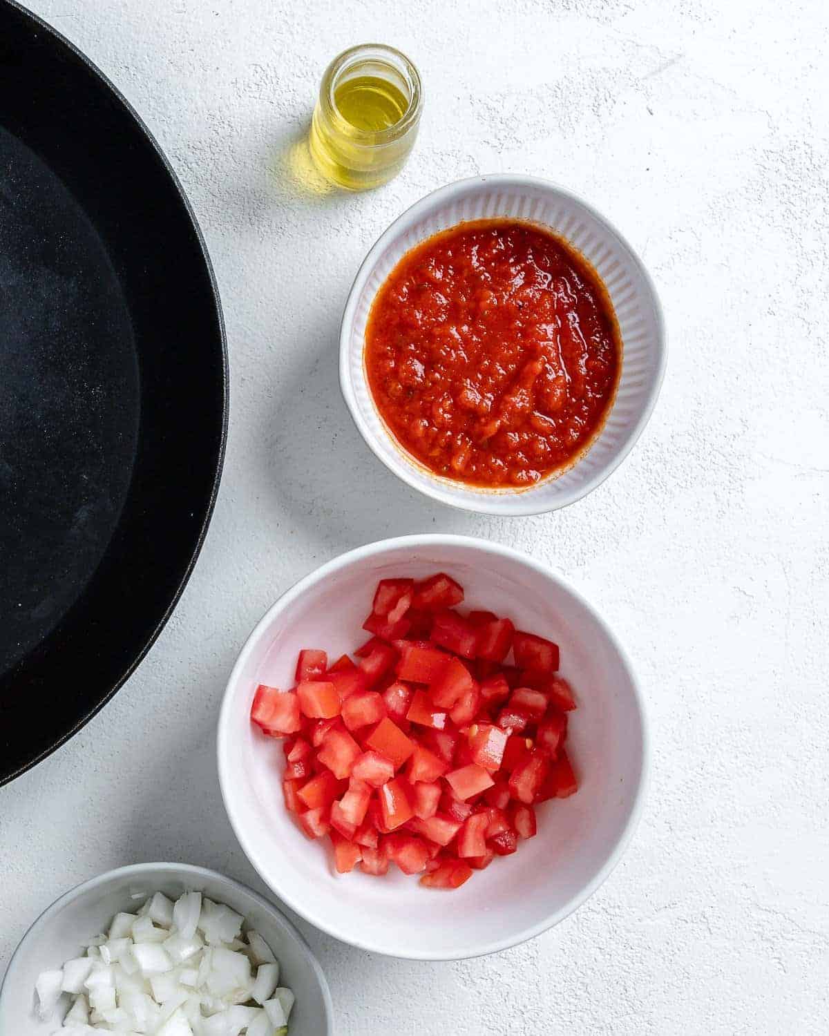diced tomatoes and marinara sauce in individual bowls against white surface