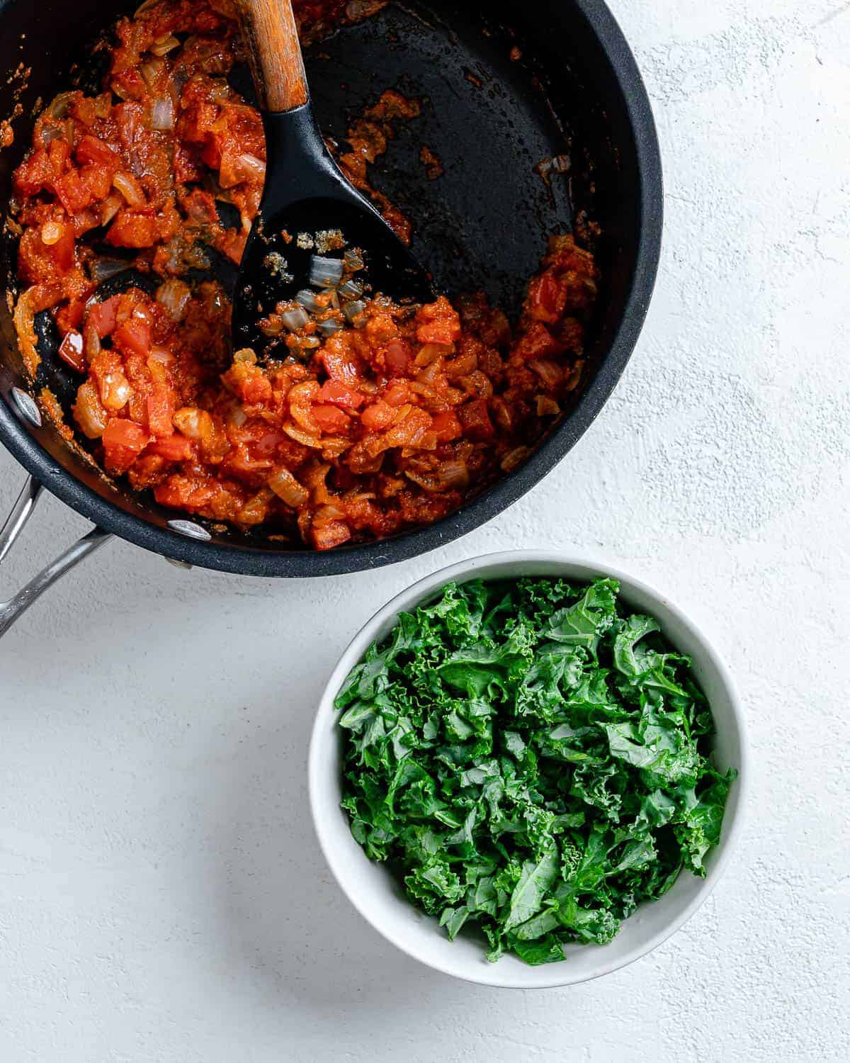 process of tomatoes and marinara in pan. alongside a white bowl of greens