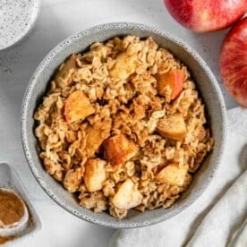 finished apple cinnamon oatmeal in a bowl with ingredients in a white background