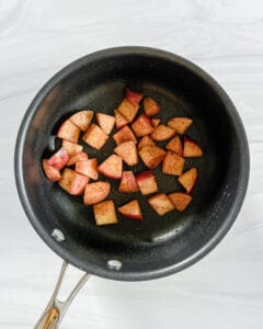 cooked cubed apples in a black pan against a white background