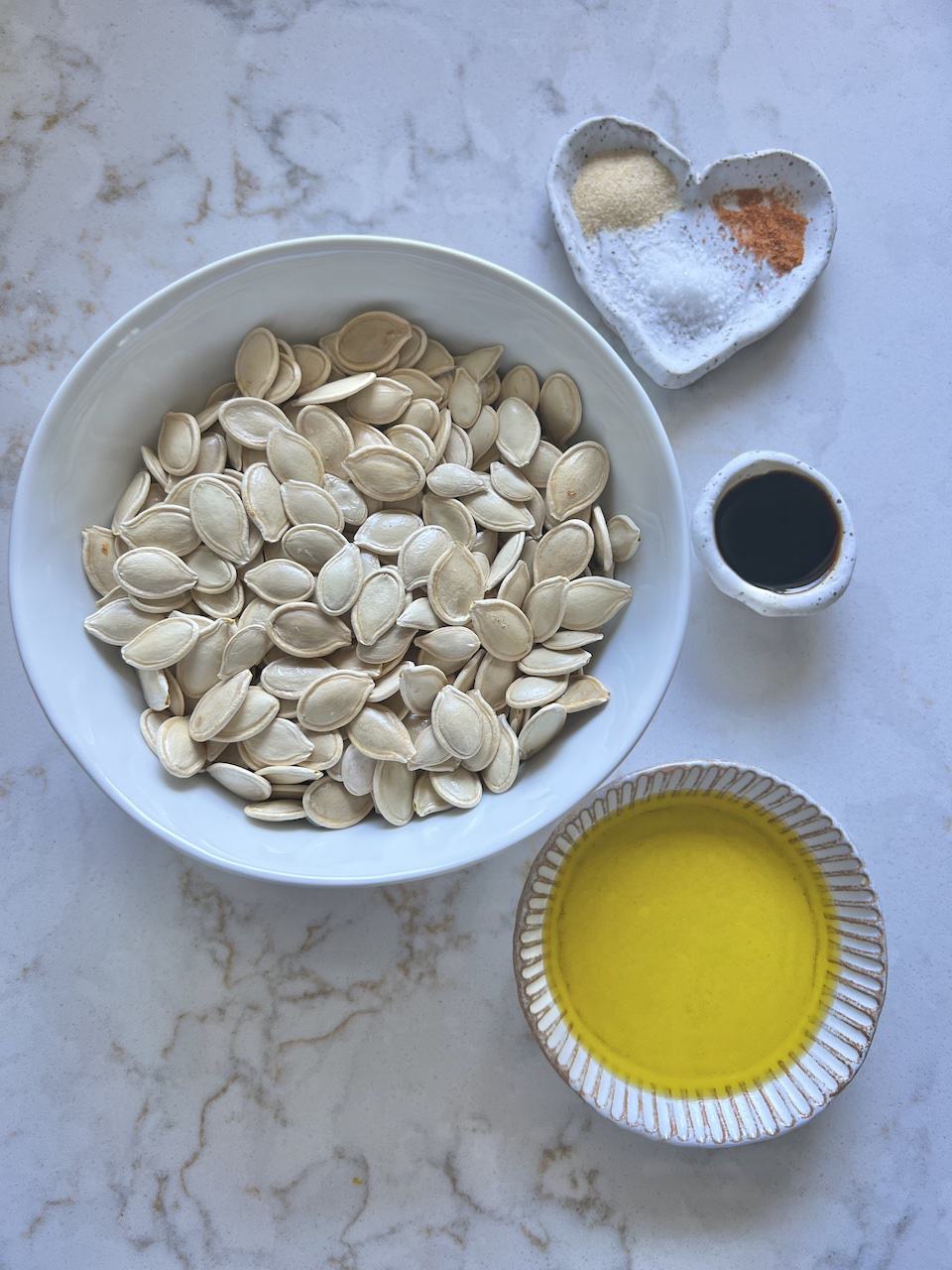ingredients for roasted ،y pumpkin seeds measured out on a white surface