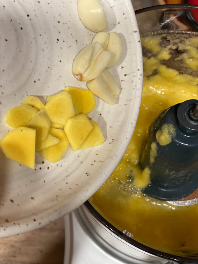process shot of adding garlic and ginger to food processor