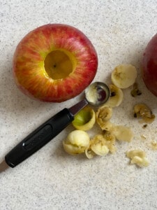 process shot showing the process of using a melon baller to remove stem and core of apple