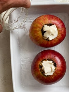 process shot of adding water to baking dish of two apples