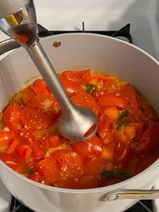process of using immersion blender in tomato basil soup