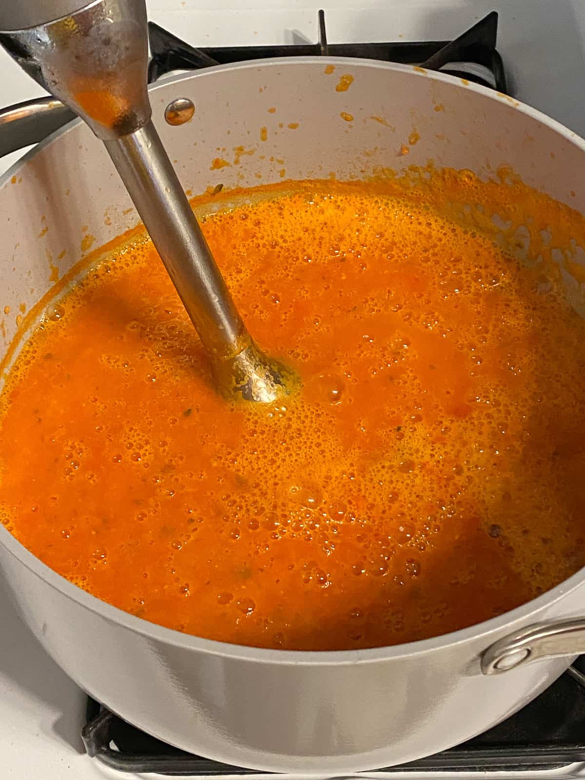 process of using immersion blender in tomato basil soup