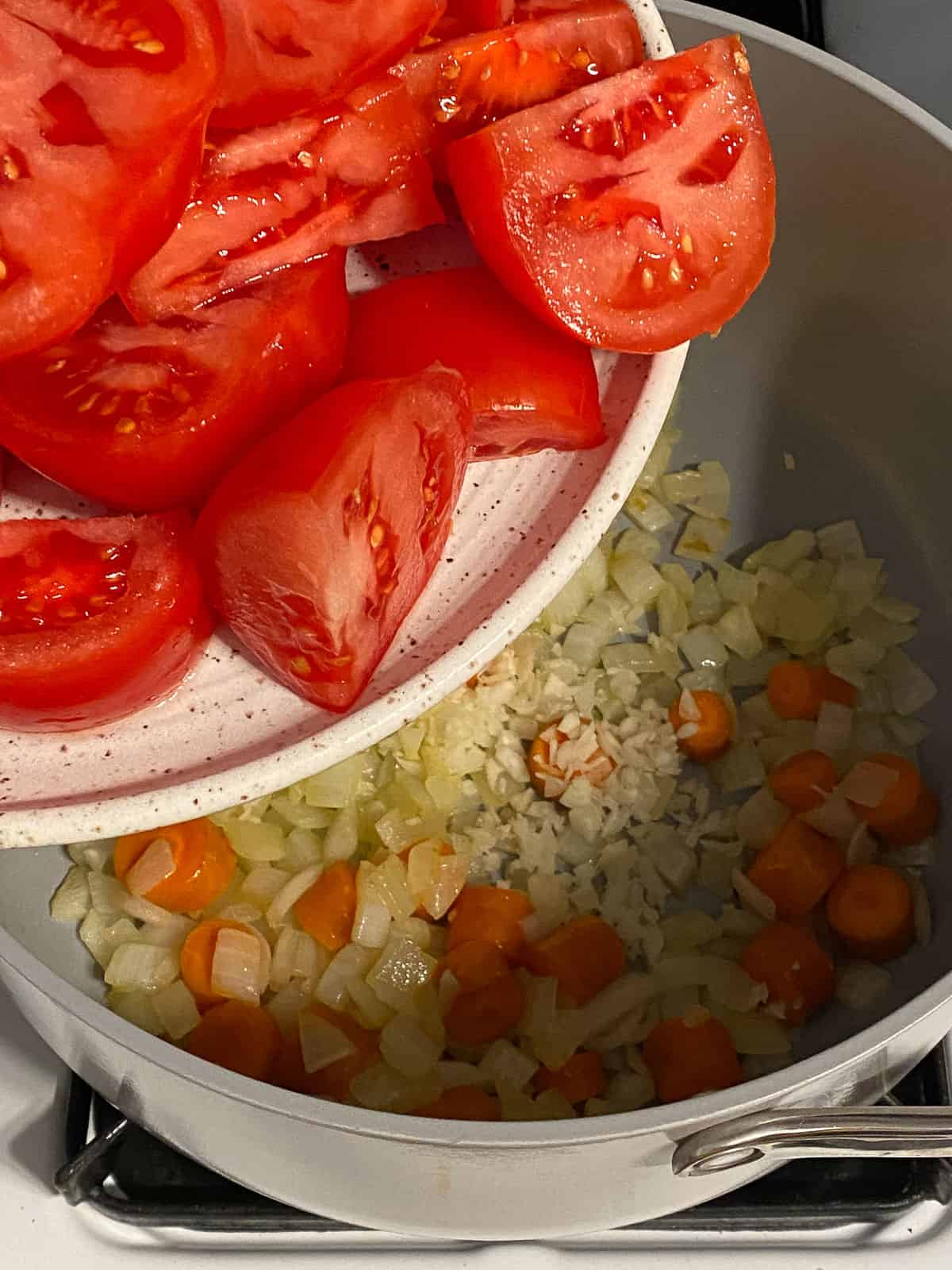 process of adding tomatoes to pan