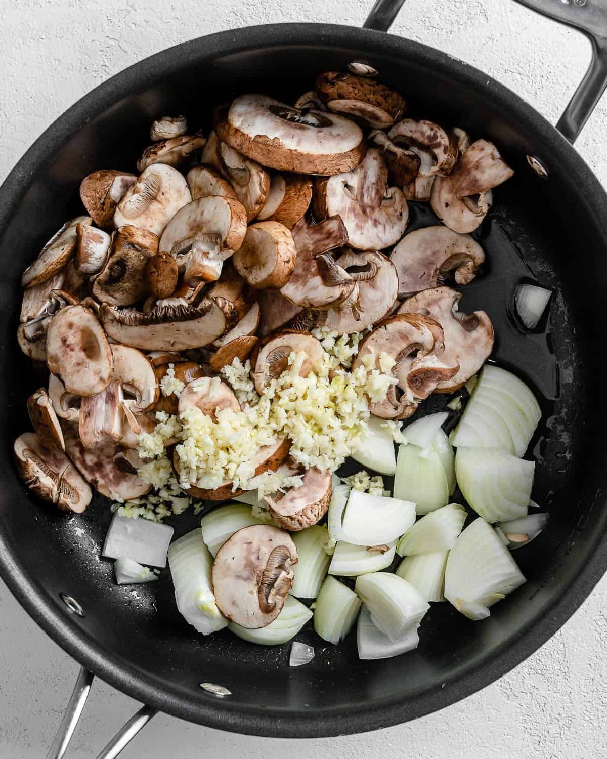 ingredients for vegan risotto added to black skillet