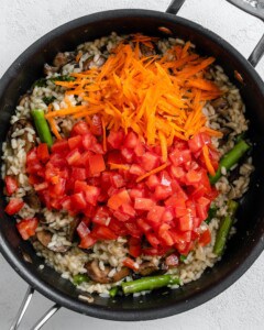 process shot of additional ingredients being added to black skillet