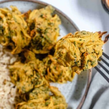 completed broccoli and onion pakora plated with a close up of one picked up with a fork