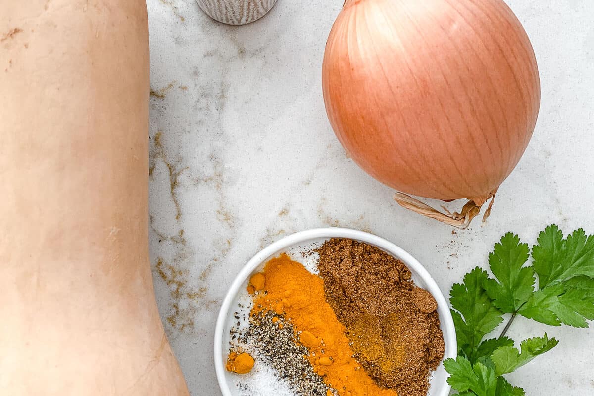 ingredients for Roasted Butternut Squash with Indian Spices and Caramelized Onions on a white marble surface
