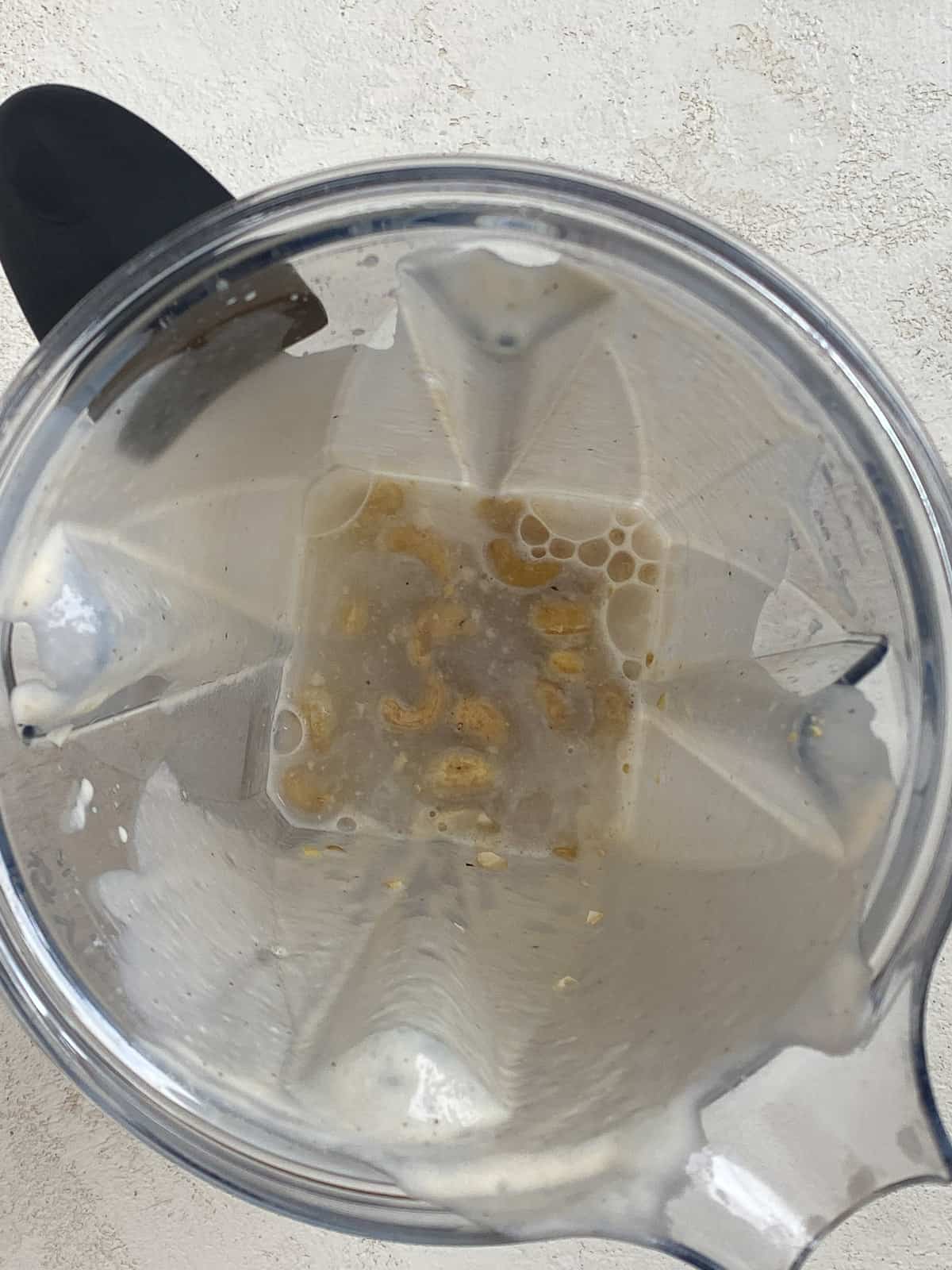 process shot of cashews and water in a blender prior to being blended