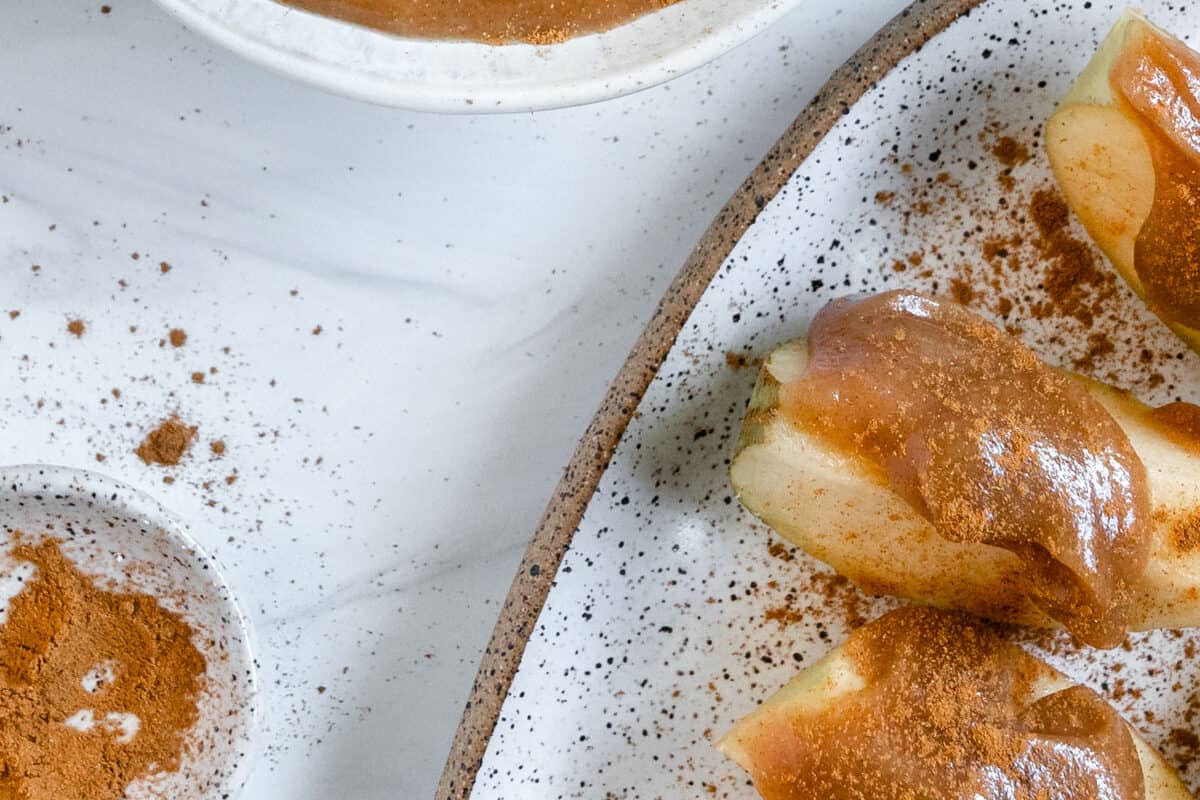 finished homemade caramel sauce in a white bowl with a spoon and dates in the background