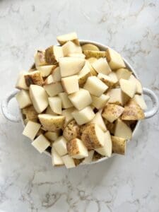 cubed and cut potatoes in a bowl against a white surface