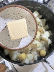 process of adding vegan butter to vegan mashed potatoes