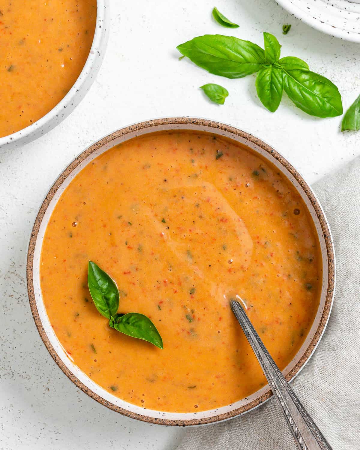 two completed Creamy Roasted Red Pepper Soup in a bowl against a light surface