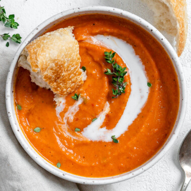 completed Vegan Tomato Bisque with Thyme in a white bowl against a light background