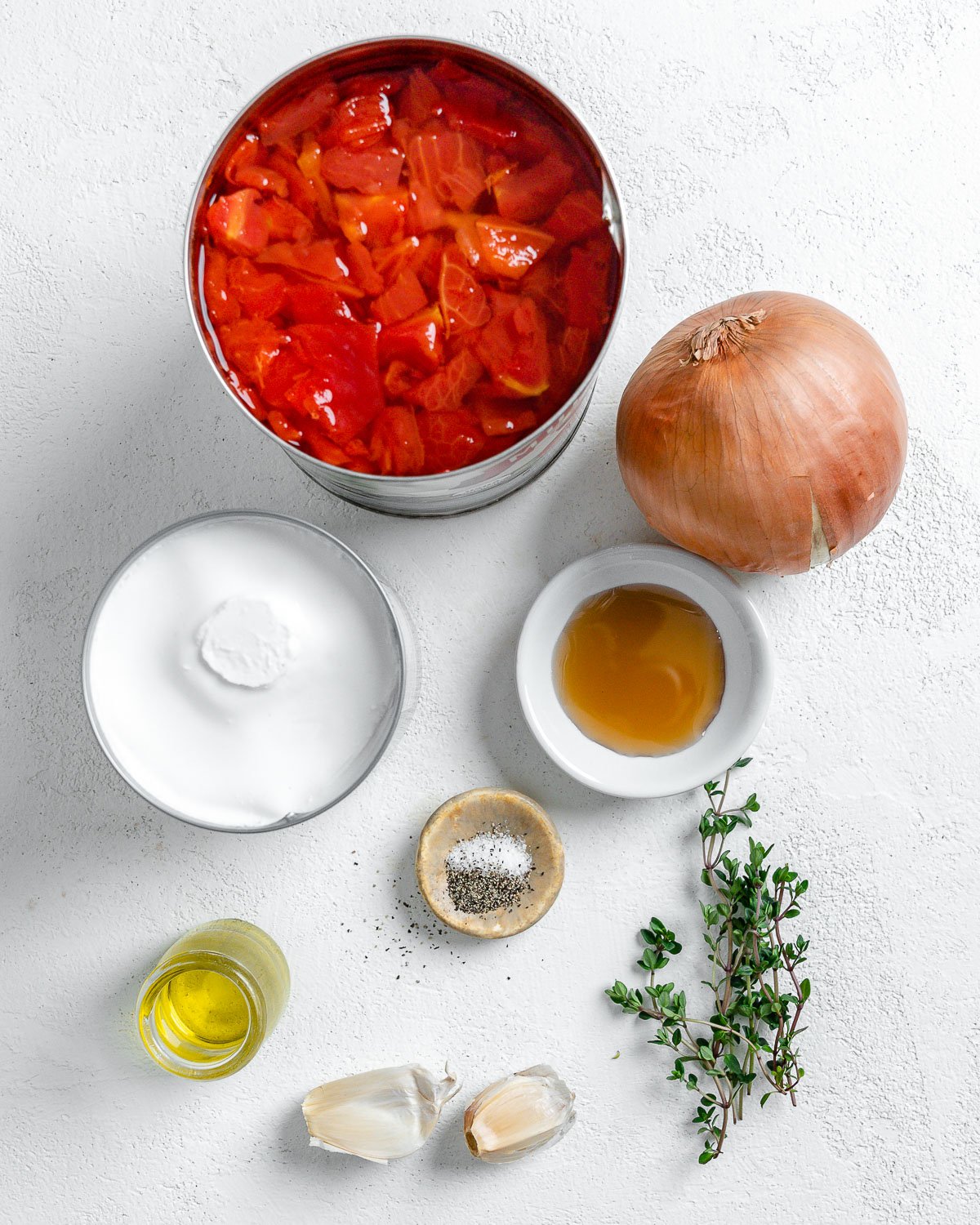 ingredients for Vegan Tomato Bisque with Thyme in individual bowls against a white surface