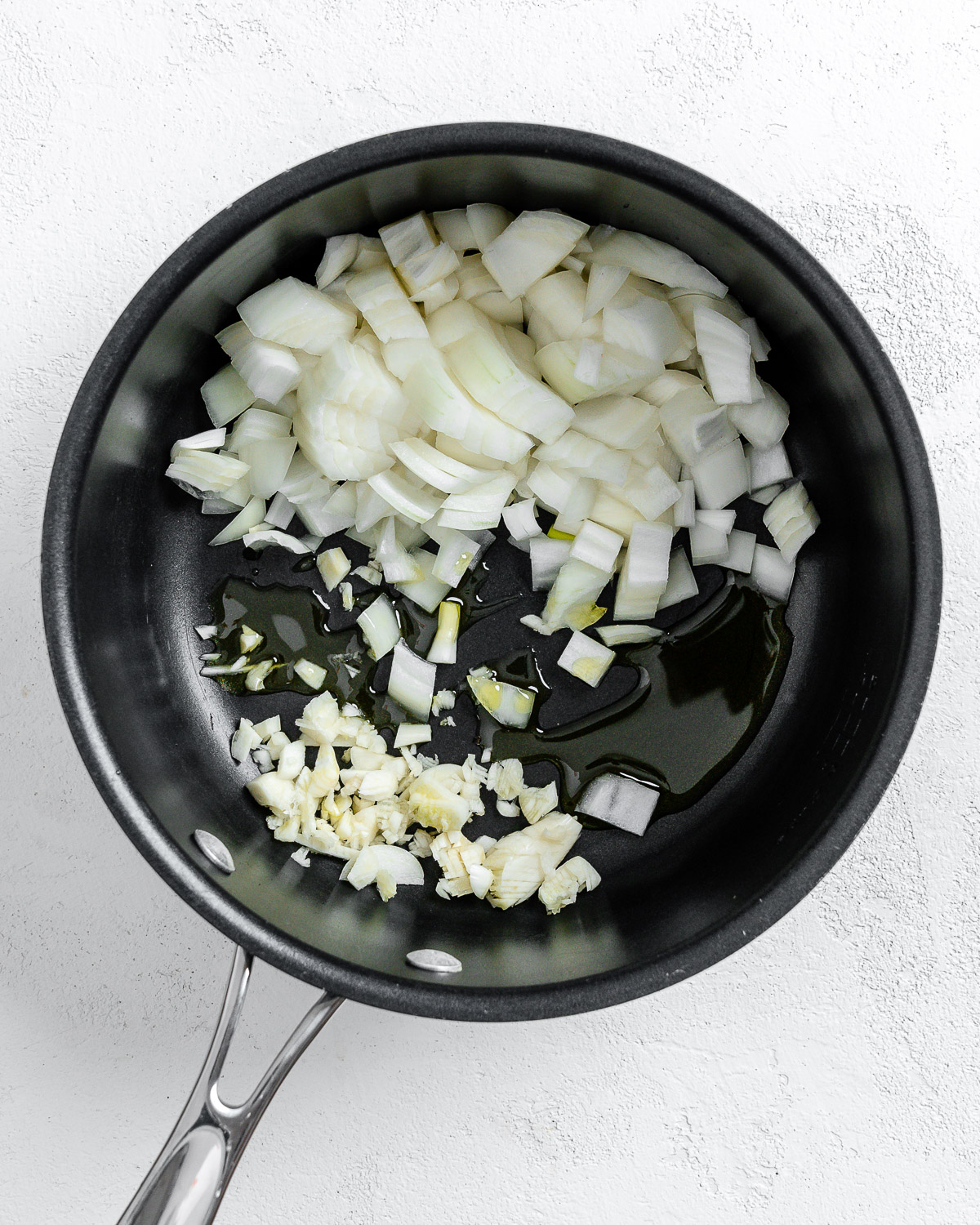 process of cooking onion and garlic in black pan against white background