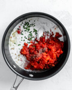 process shot showing addition of spices and herbs to black pan
