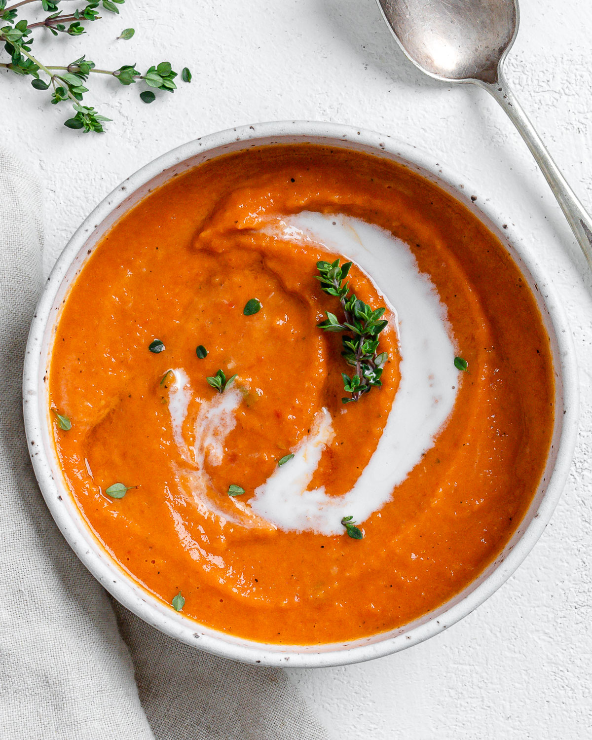completed Vegan Tomato Bisque with Thyme in a white bowl against a light background