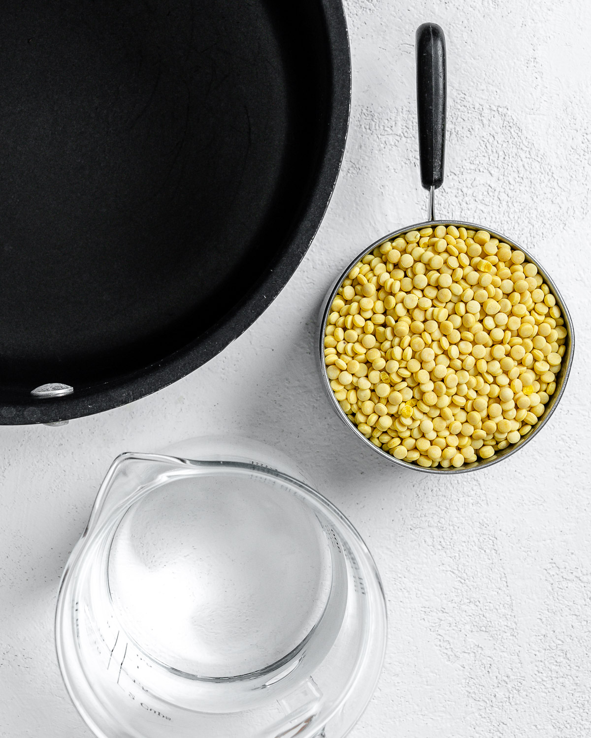 skillet alongside water and couscous against a white surface