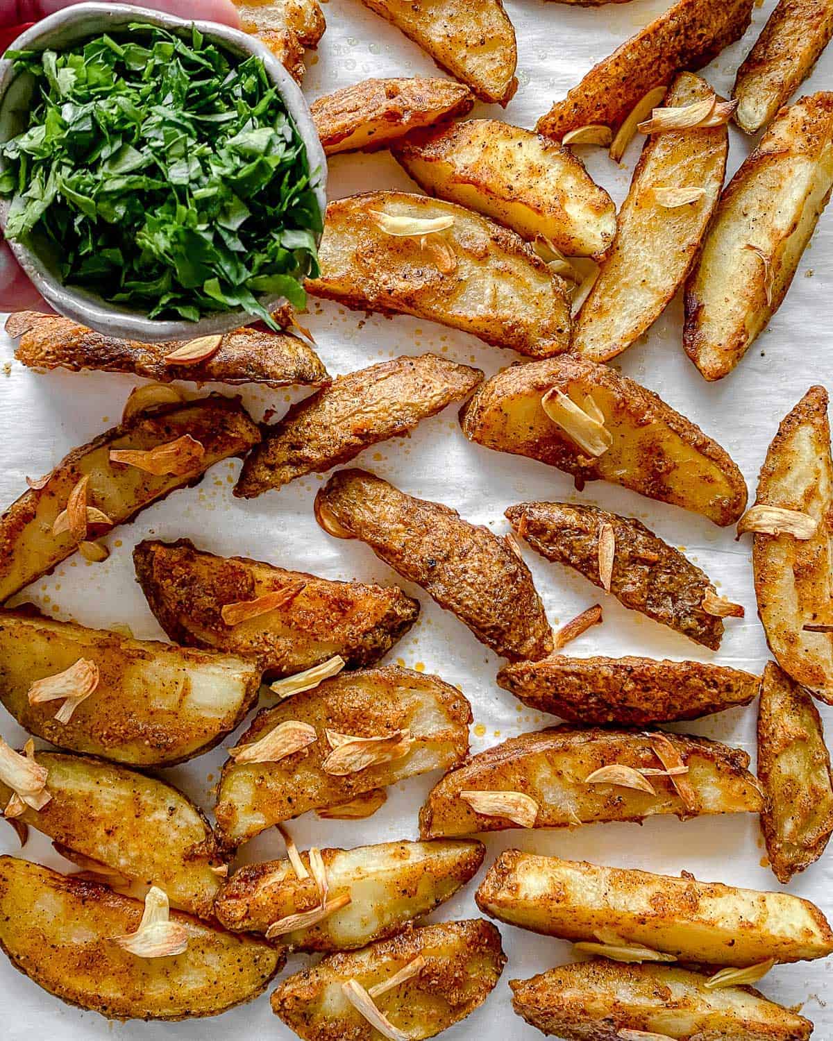 completed Oven Baked Garlic Parsley Fries scattered on a baking tray