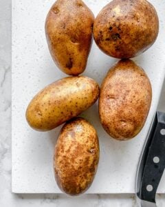 5 russet potatoes on a cutting board