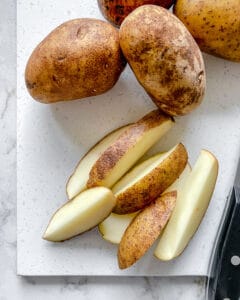 process of making wedges from russet potatoes on white surface