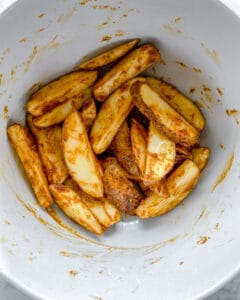 mixed potato wedges with seasonings in white bowl