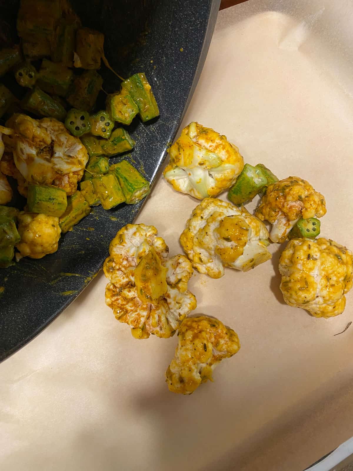 process shot of tossing okra and cauliflower to baking sheet