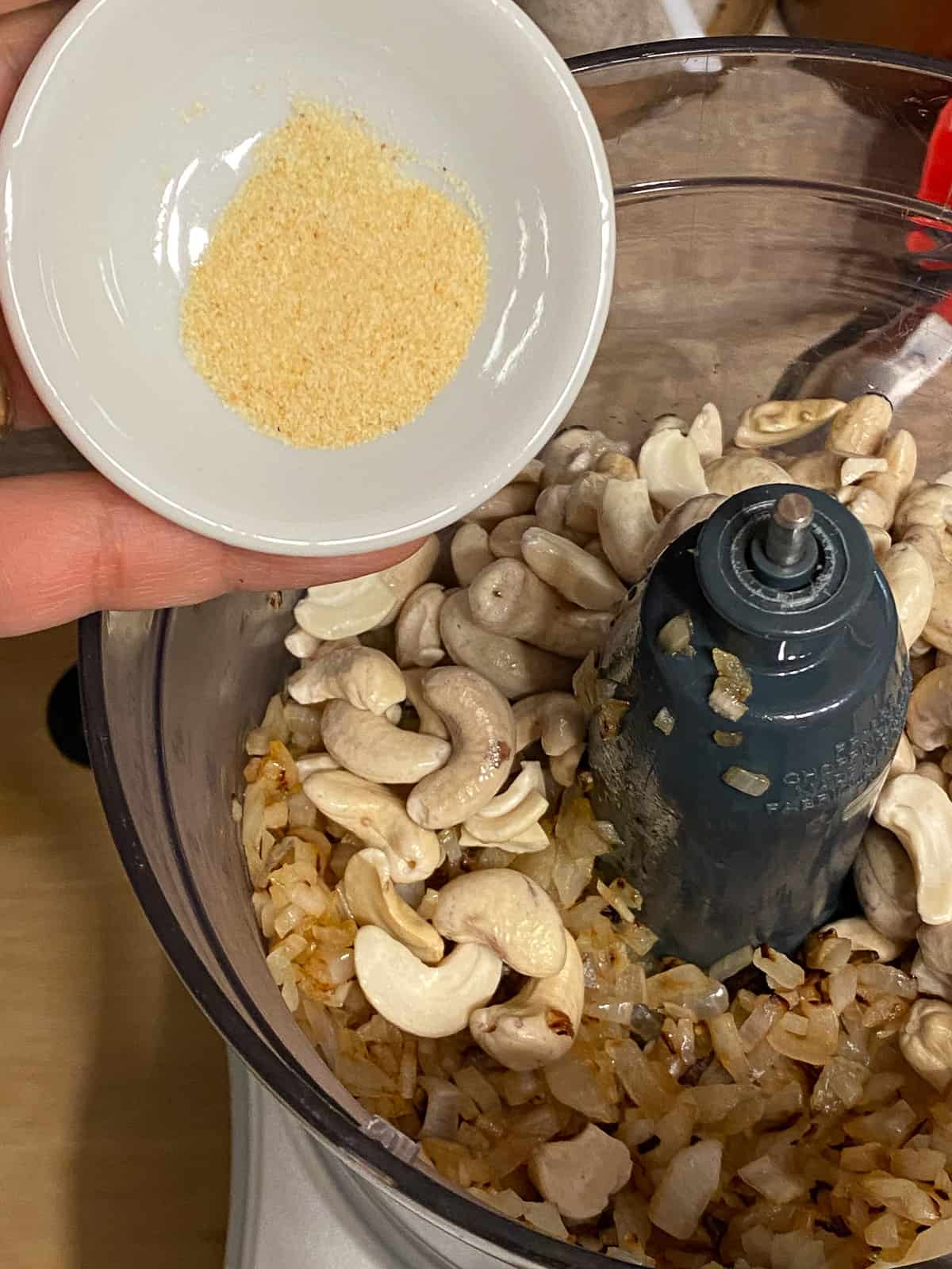 process shot of adding garlic to food processor