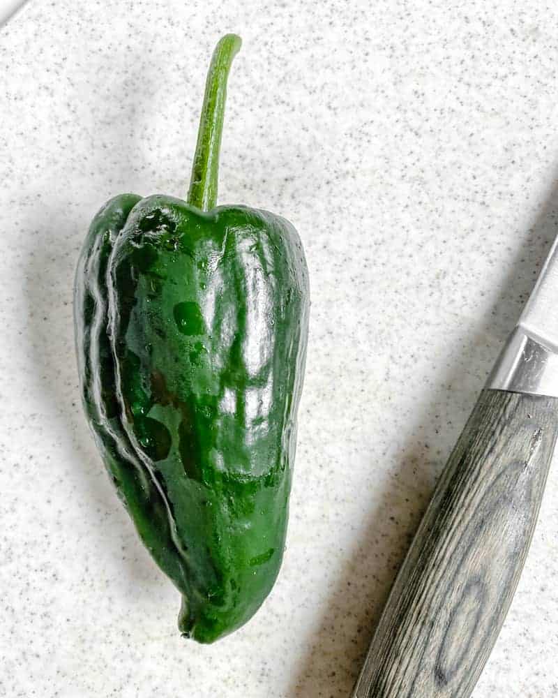 green pepper with knife against a white background