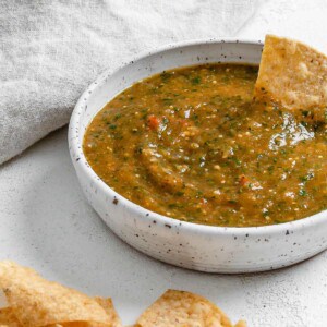 completed Stovetop Tomatillo Salsa in a bowl with a chip being dipped in it